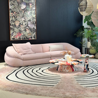 RINGCHEN modern curved cloud sofa featuring premium blush textured upholstery, highlighted by its signature sculptural low-profile silhouette, channel-tufted base detailing, and deep-seated organic cushioning for a high-end minimalist living room aesthetic.-Three quarter view