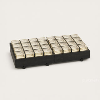 RINGCHEN sculptural coffee table with a grid of textured amber glass blocks set within a low-profile matte black wooden frame, highlighting the interplay of light through artisanal thick glass bricks, creating a sophisticated geometric cocktail table with a modern architectural silhouette and subtle spherical feet for a minimalist, grounded luxury aesthetic.-Three quarter studio view