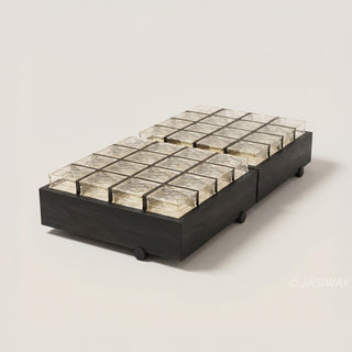 RINGCHEN sculptural coffee table with a grid of textured amber glass blocks set within a low-profile matte black wooden frame, highlighting the interplay of light through artisanal thick glass bricks, creating a sophisticated geometric cocktail table with a modern architectural silhouette and subtle spherical feet for a minimalist, grounded luxury aesthetic.-Diagonal studio view