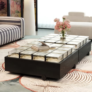 RINGCHEN sculptural coffee table with a grid of textured amber glass blocks set within a low-profile matte black wooden frame, highlighting the interplay of light through artisanal thick glass bricks, creating a sophisticated geometric cocktail table with a modern architectural silhouette and subtle spherical feet for a minimalist, grounded luxury aesthetic.-Diagonal view