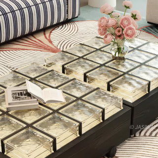 RINGCHEN sculptural coffee table with a grid of textured amber glass blocks set within a low-profile matte black wooden frame, highlighting the interplay of light through artisanal thick glass bricks, creating a sophisticated geometric cocktail table with a modern architectural silhouette and subtle spherical feet for a minimalist, grounded luxury aesthetic.-Close-up of glass top