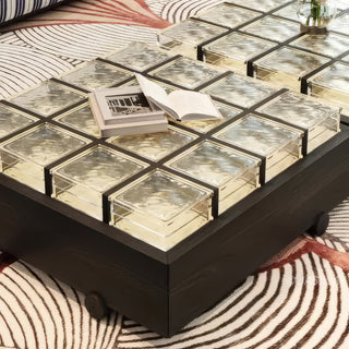 RINGCHEN sculptural coffee table with a grid of textured amber glass blocks set within a low-profile matte black wooden frame, highlighting the interplay of light through artisanal thick glass bricks, creating a sophisticated geometric cocktail table with a modern architectural silhouette and subtle spherical feet for a minimalist, grounded luxury aesthetic.-Close-up of edge and base