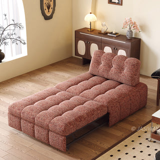 A rust red tufted chenille convertible sleeper sofa is fully extended into a sleeper bed setup in a cozy, warmly lit modern living room.