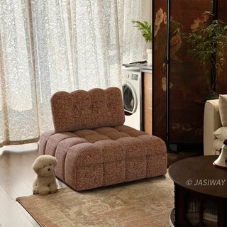 A rust red tufted chenille convertible sleeper sofa is styled in a cozy living room with a cute toy dog on the rug and sheer curtains in the background.
