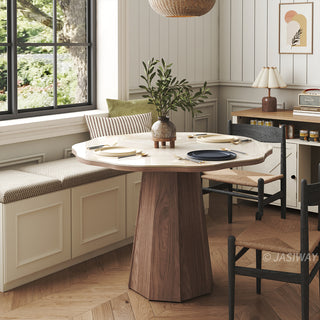Lifestyle shot of a cozy dining nook featuring a modern round sintered stone dining table with a solid wooden pedestal base, paired with woven black dining chairs and a built-in window banquette seating arrangement.