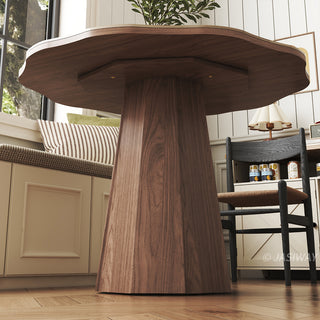 Low-angle detail shot of a modern sintered stone dining table highlighting its unique faceted wooden pedestal base and organic shape in a warm dining space.